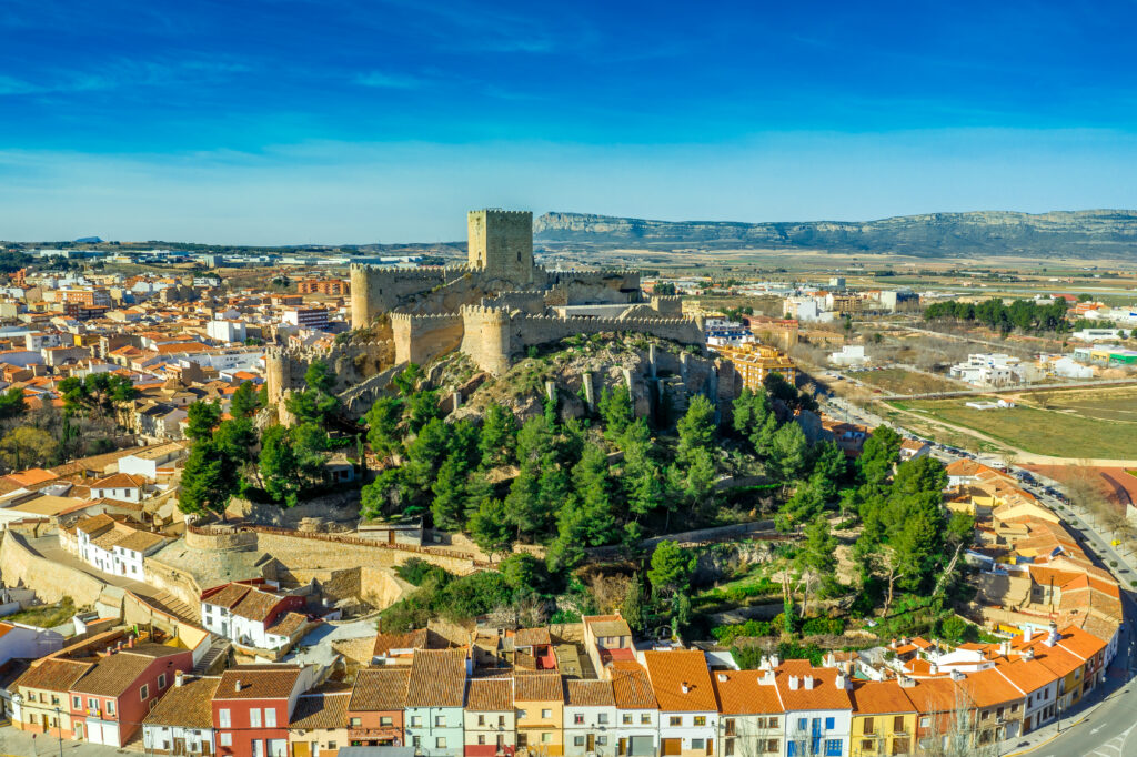 Aerial view of medieval Almansa castle with donjon and courtyard surrounded by a circular ring of red roof houses in Spain