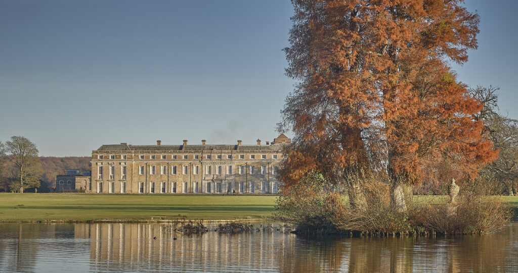 Petworth stately home with lake an golden tree in autumn