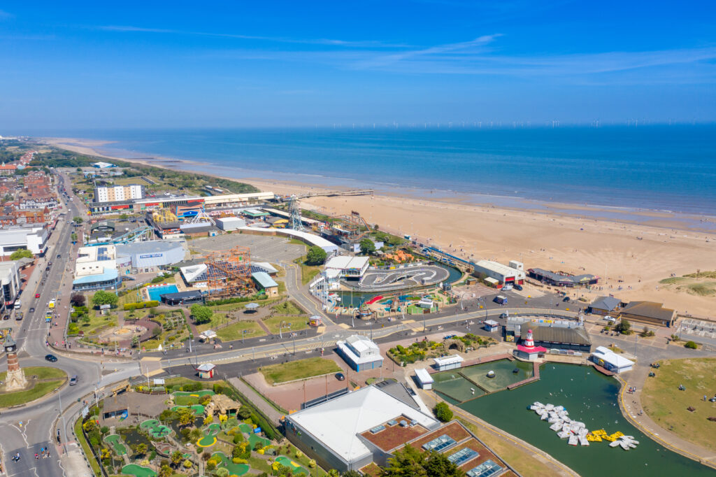 Aerial photo of the town centre of Skegness showing the pier on the sandy beach near fairground rides in the East Lindsey district of Lincolnshire, England