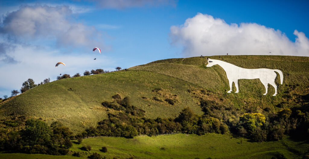 View of Westbury White Horse in Wiltshire, UK with  paragliders floating above