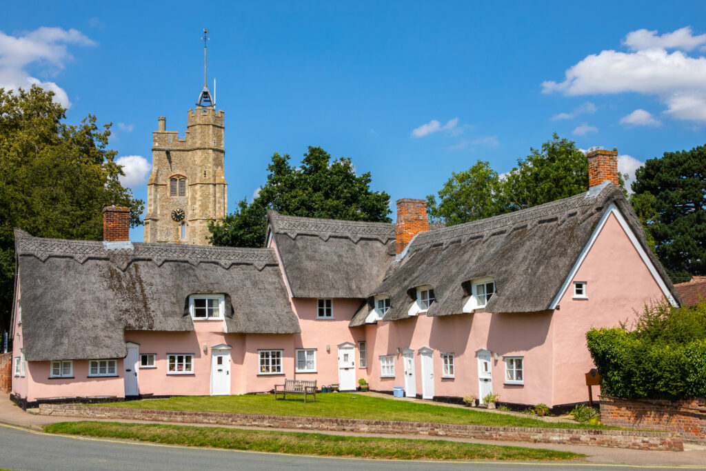 The picturesque view of St. Mary the Virgin church and the pink cottages in the village of Cavendish in Suffolk, UK