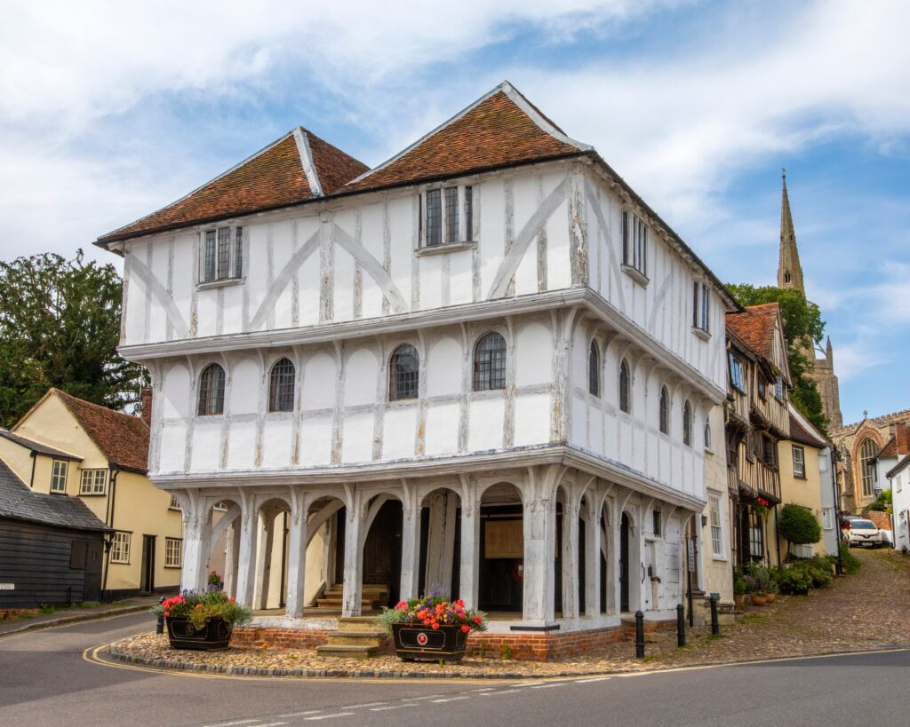 Essex, UK - September 6th 2021: A view of the historic Thaxted Guildhall, in the picturesque town of Thaxted in Essex, UK.  The spire of Thaxted Parish Church is seen in the distance.