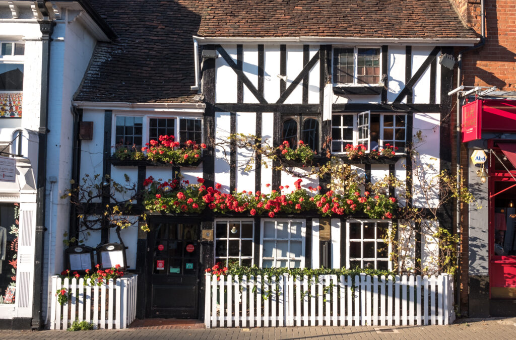 Photo of Friends Restaurant in Pinner High Street. Restaurant is located in historic timber tudor building. Red geraniums are growing on the outside.