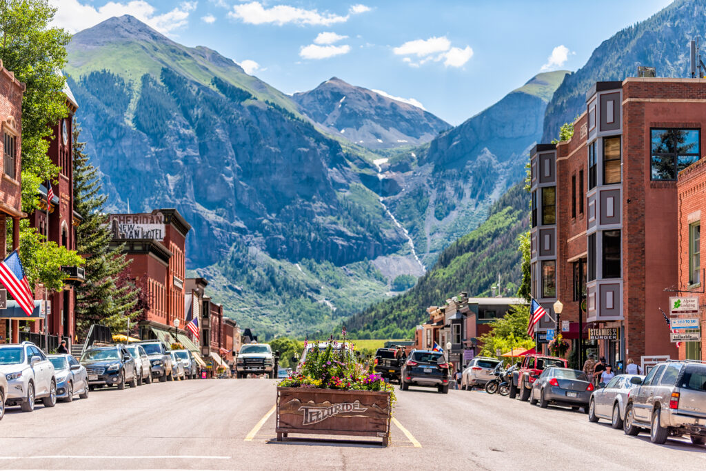 Telluride, USA: Small town village in Colorado with sign for city and flowers by historic architecture on main street mountain view