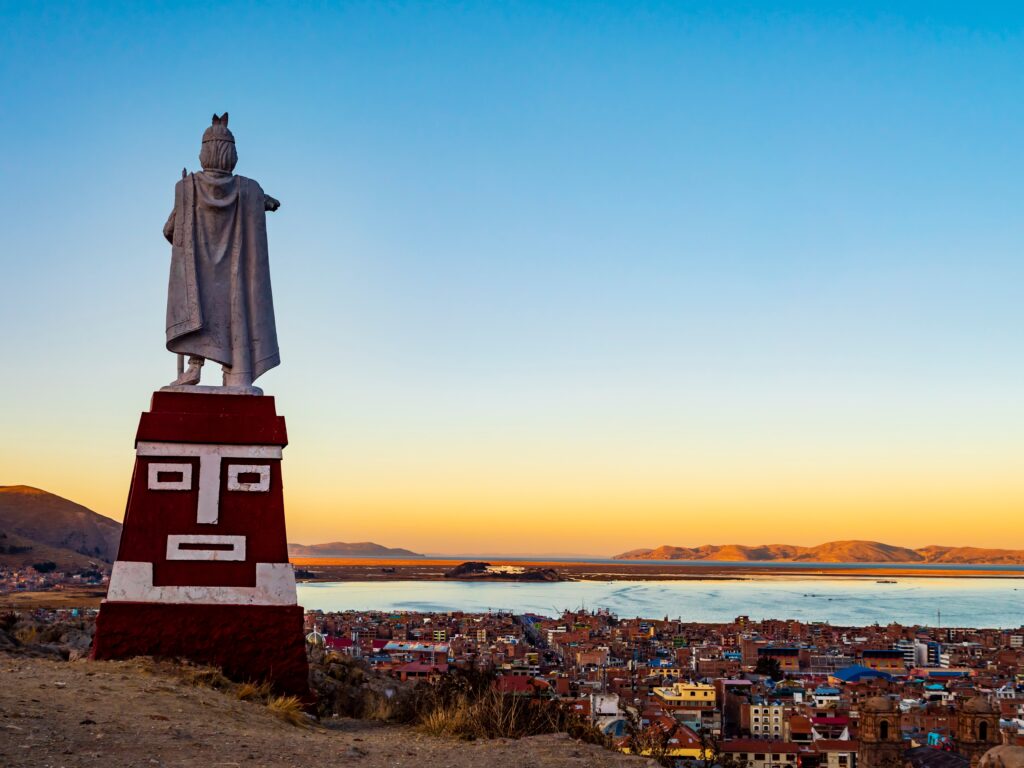 Puno, Peru: Stunning aerial view of lake Titicaca at sunset from Huajsapata Hill viewpoint with the monument to Manco Capac in foreground