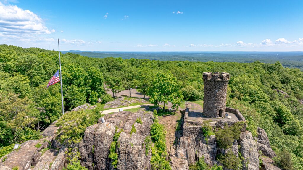 Castle Craig, Meriden, CT with flag at half mast. Aerial drone photo with horizon and blue sky.