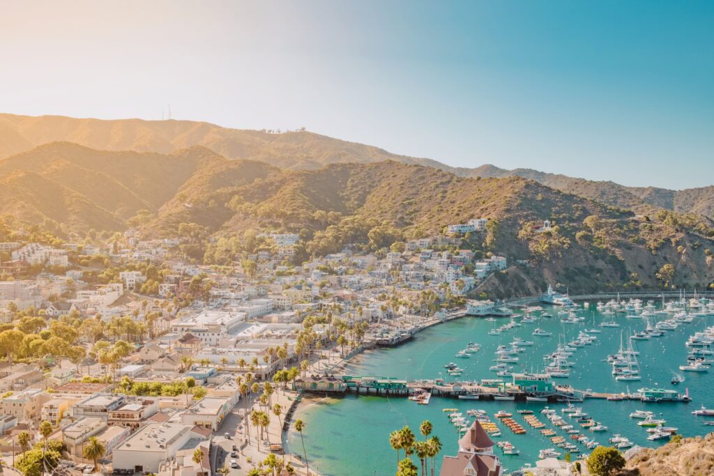 CATALINA ISLAND, US: Scenic view of Avalon Bay, Catalina Island, with boats in the harbor and hills in the background under a clear blue sky.