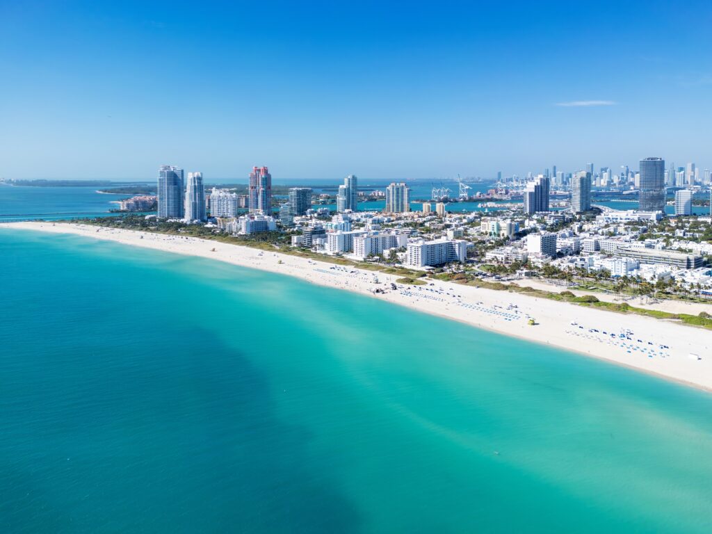Miami Beach on blue sky. Skyline aerial view. Miami city. Tropical Miami scene. Miami district sky view. Famous oceanfront. Panoramic coastline. South beach panorama view. Summer holiday vibes.