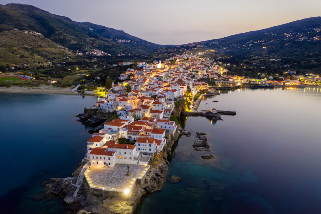 Aerial view over the beautiful illuminated town of Andros island, Cyclades, Greece, during dusk time