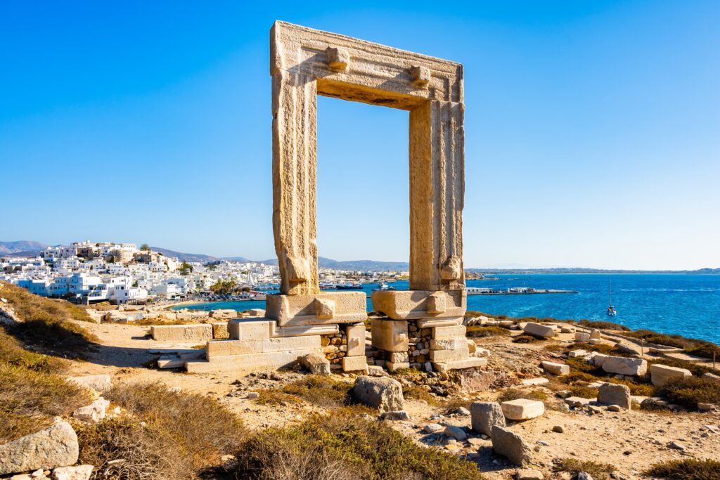 Portara monument also known as Temple of Apollo overlooking port and town on sea coast, Naxos island, Cyclades, Greece