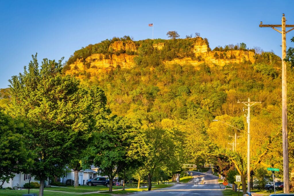 Grandad Bluff at sunset overlooking La Crosse Wisconsin with glowing sky, city view, and scenic sandstone cliff formation.