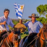 Gauchos riding horses and waving the Uruguayan flag in Uruguay, South America