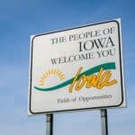 Iowa welcome roadside sign against blue sky at state border with Missouri, travel concept