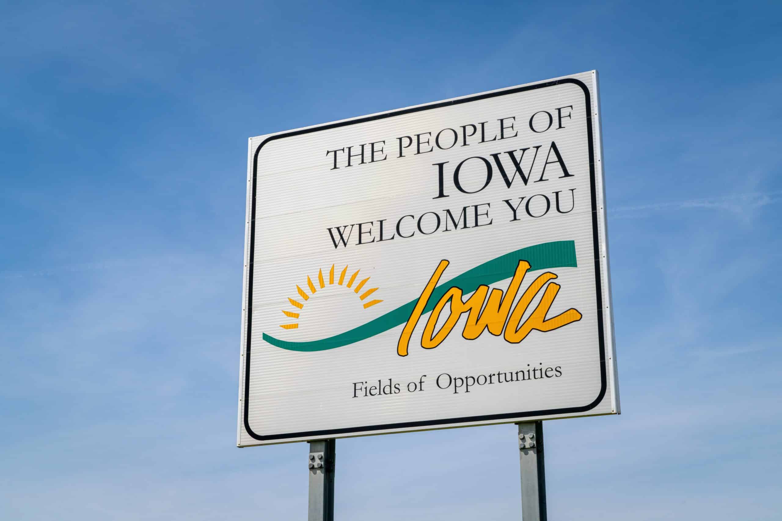 Iowa welcome roadside sign against blue sky at state border with Missouri, travel concept