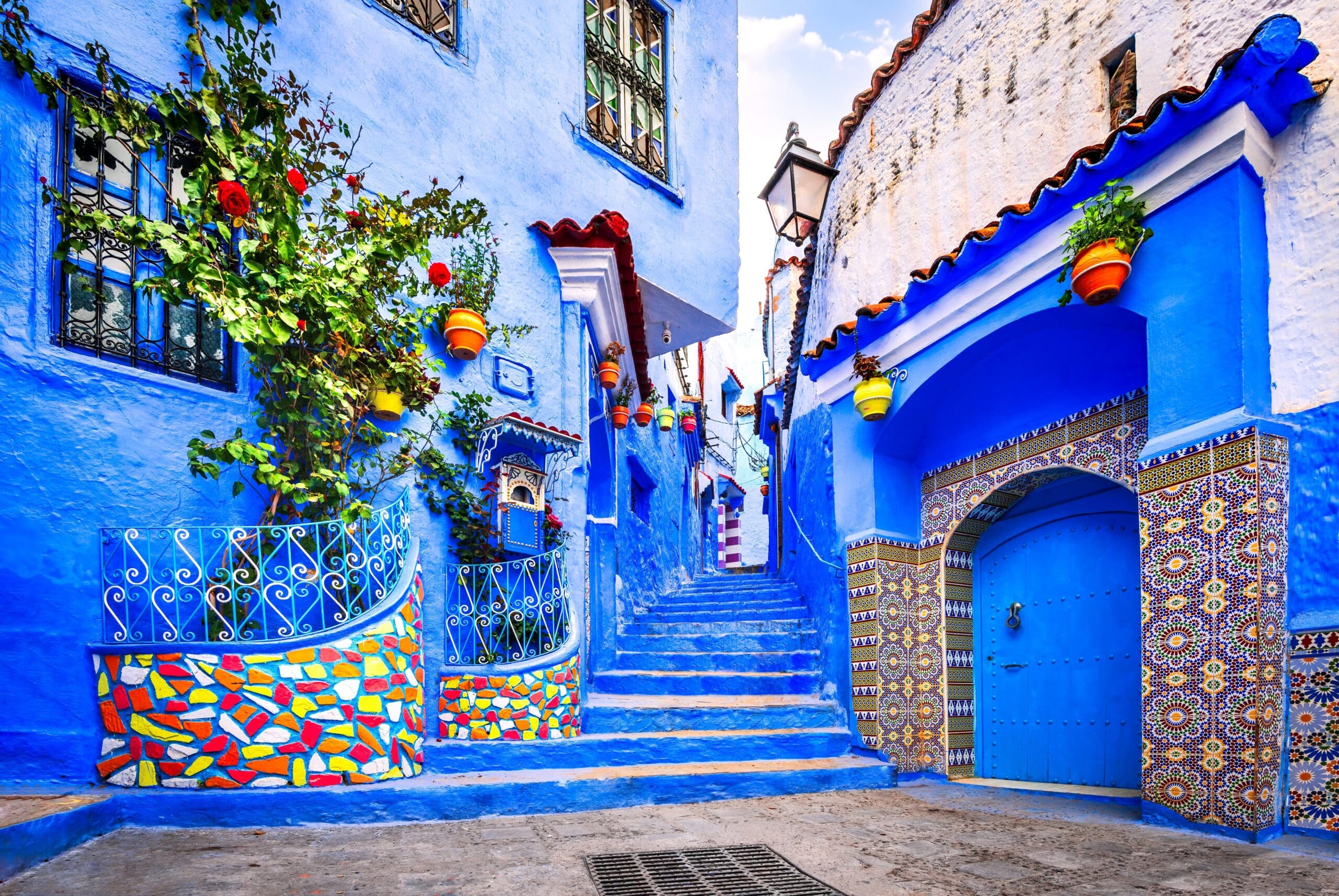 Chefchaouen, Morocco. Blue staircase and wall decorated with colorful flowerpots, North Africa travel destination.