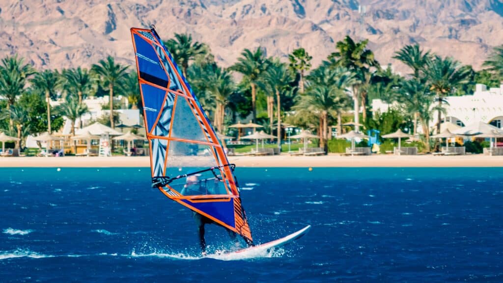 windsurfer rides on the background of the beach with a hotel and palm trees in Egypt Dahab