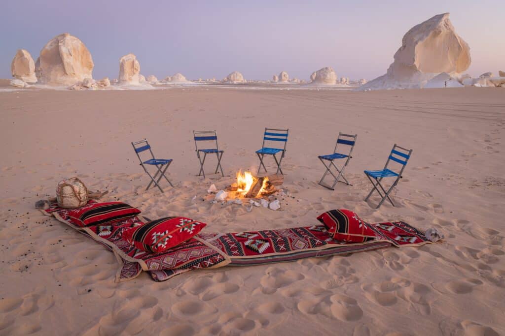 White Desert National Park, Al Farafra, New Valley, Egypt. Chairs, rugs, pillows around a campfire, ust after sunset in the White Desert of western Egypt.