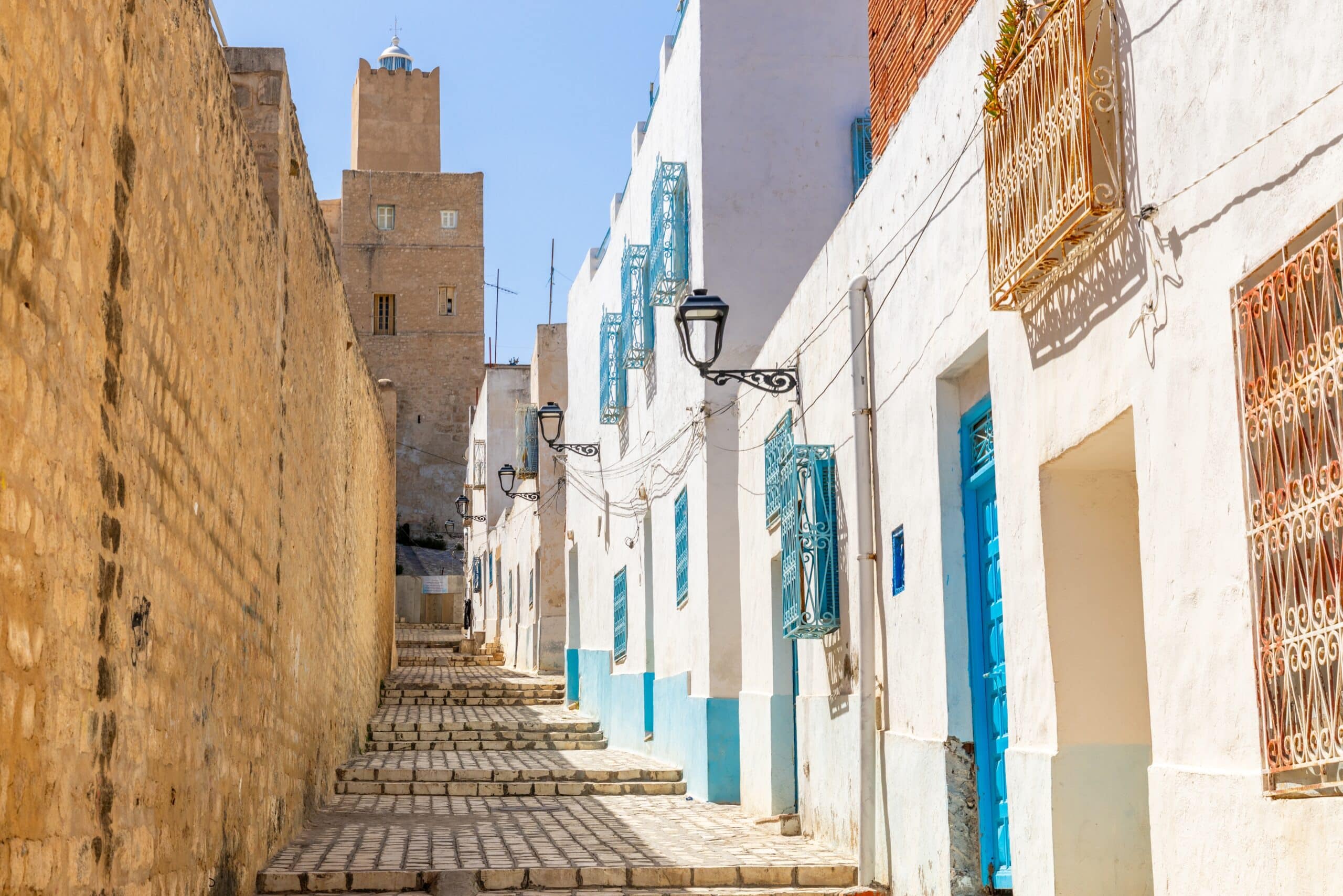 Narrow cobblestone street with blue doors and the Kasbah tower, Sousse, Tunisia