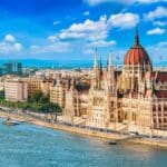 Parliament and Danube riverside in Budapest Hungary with sightseeing ship during summer sunny day with blue sky and clouds