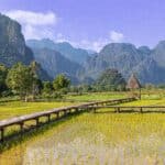 Vang Vieng, Laos - A breathtaking view of South East Asia natural beauty, with rolling mountains and lush rice fields stretching into the horizon.