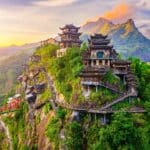 Beautiful ancient village with traditional wooden buildings on the green mountain at sunrise in Jiangxi, China.