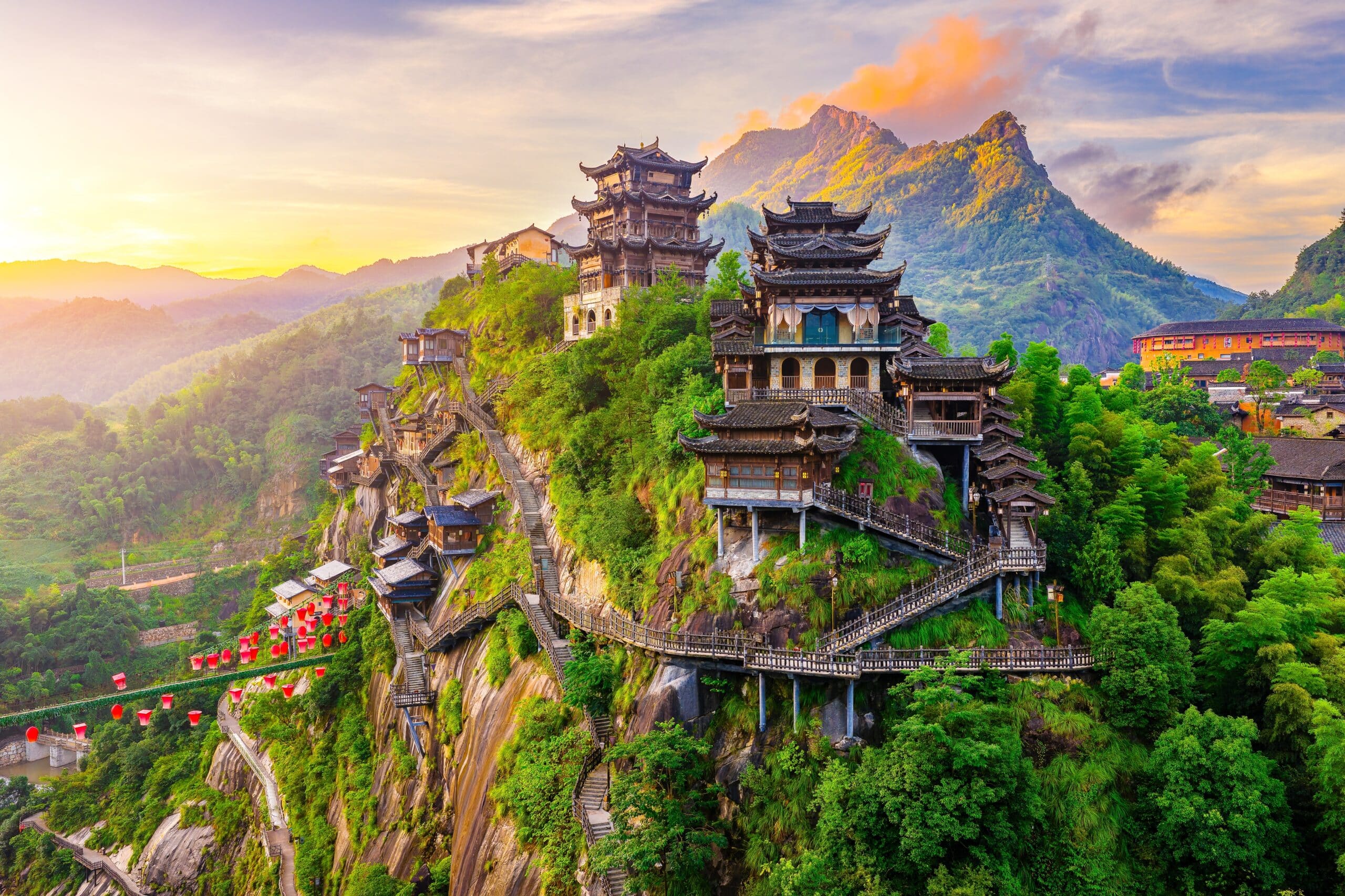 Beautiful ancient village with traditional wooden buildings on the green mountain at sunrise in Jiangxi, China.