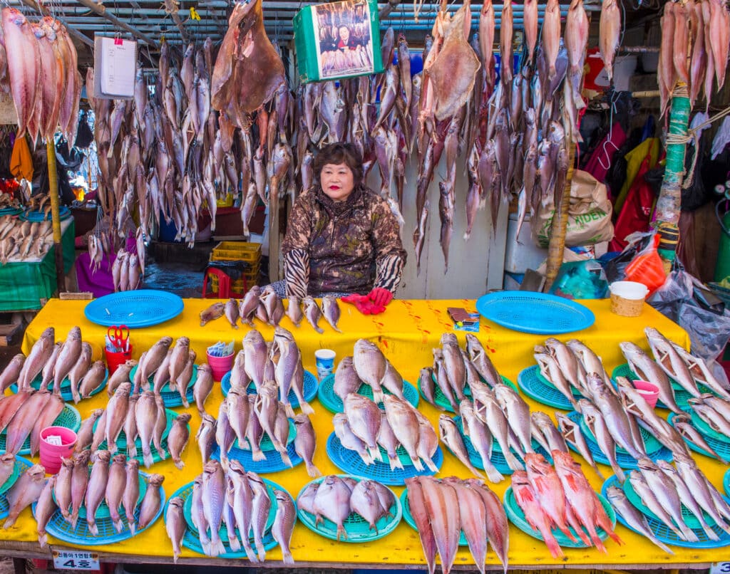 Fish vendor at a Korean market with dried seafood displayed on tables