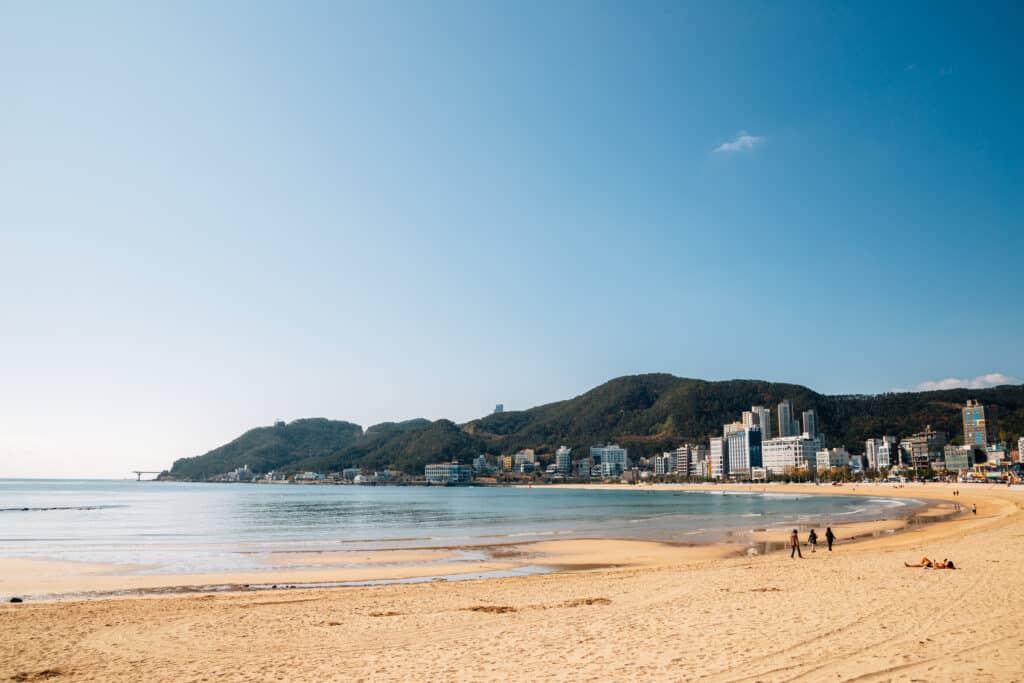 Songjeong Beach in Busan with sandy shore, gentle waves, and coastal city backdrop