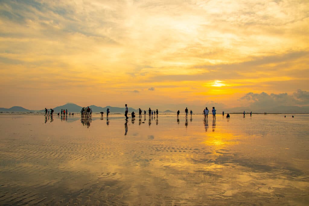 People walking on wet sand during sunset at Dadaepo Beach Busan