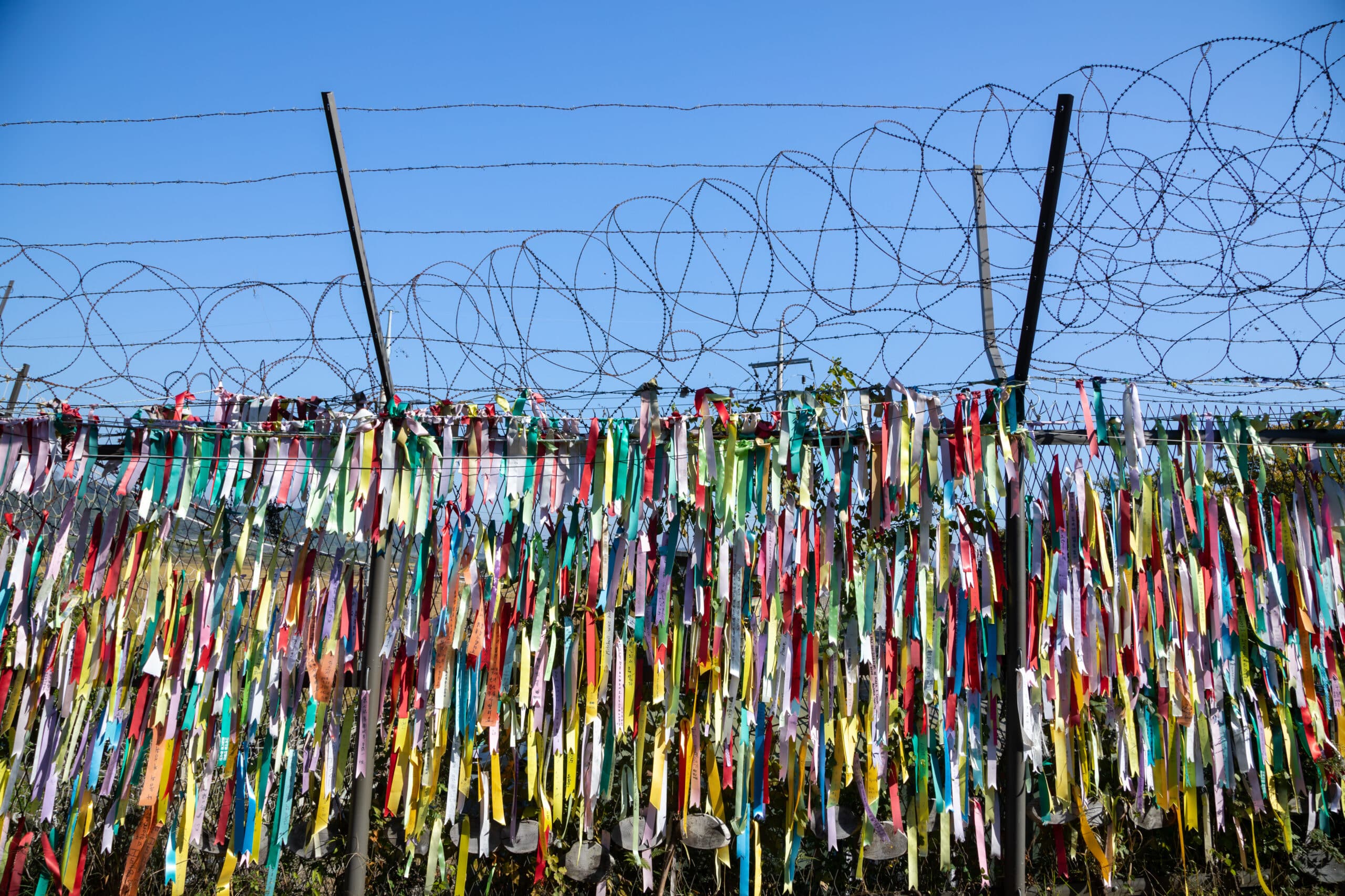 Barbed wire fence with colorful peace ribbons at Korean DMZ border