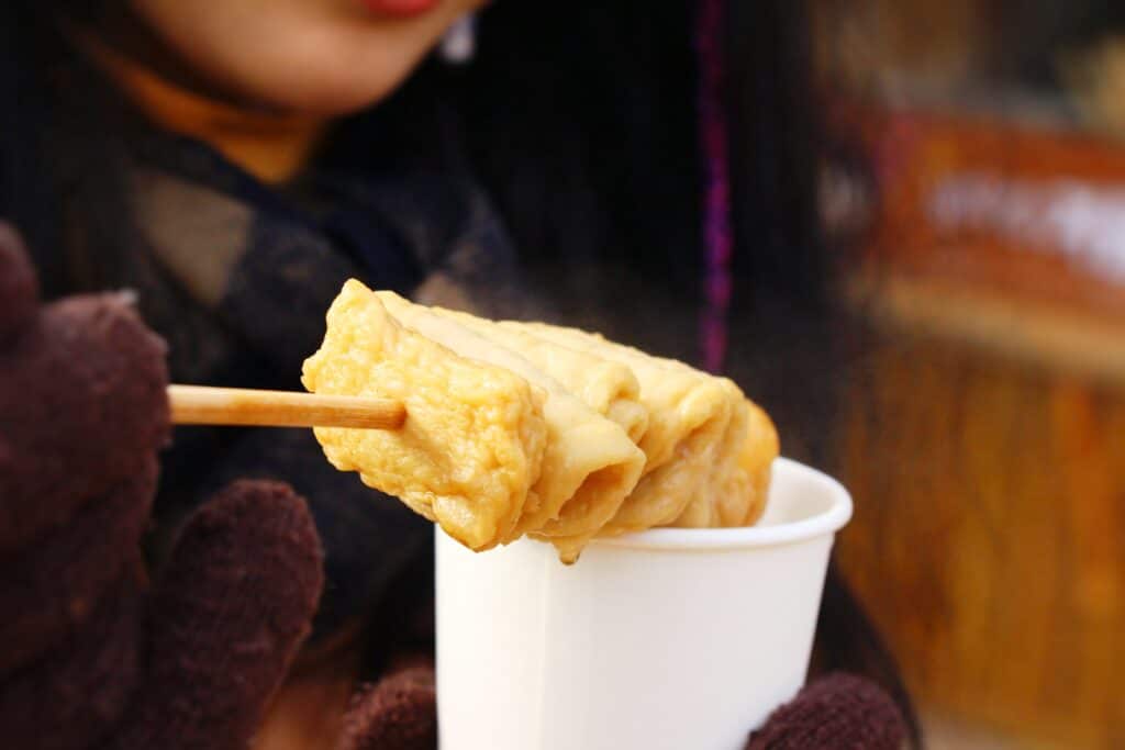 Korean odeng fish cake skewer served in a cup with hot broth at a street food stall