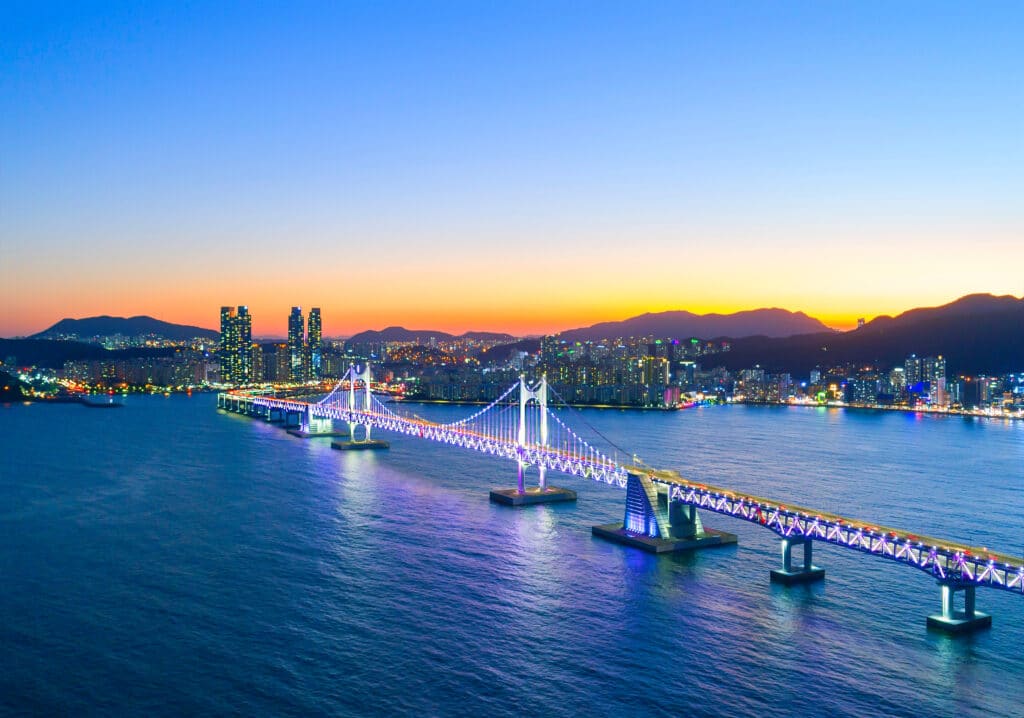Gwangan Bridge illuminated at night over the ocean in Busan