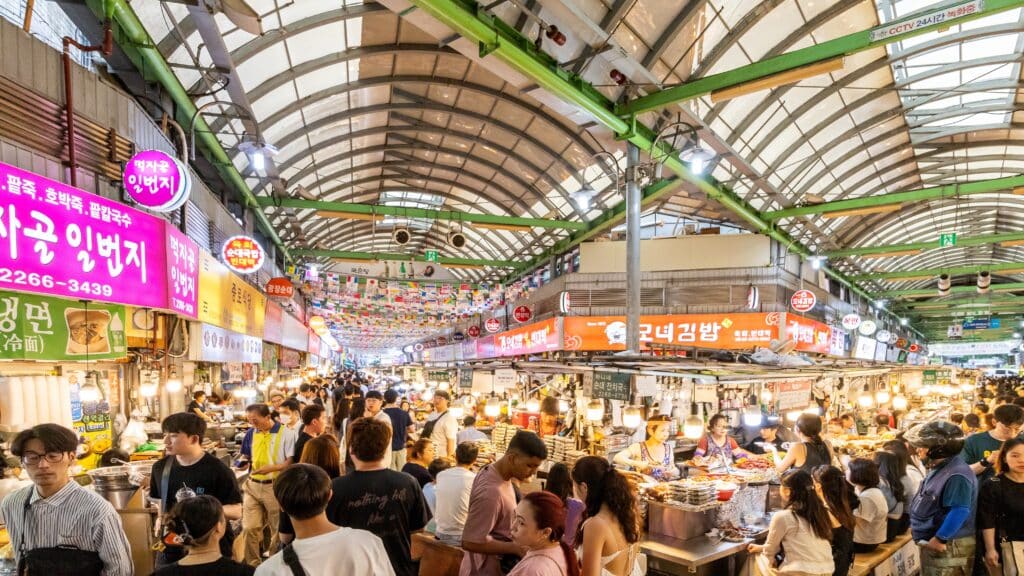Korean street food vendor serving customers at a traditional indoor market stall