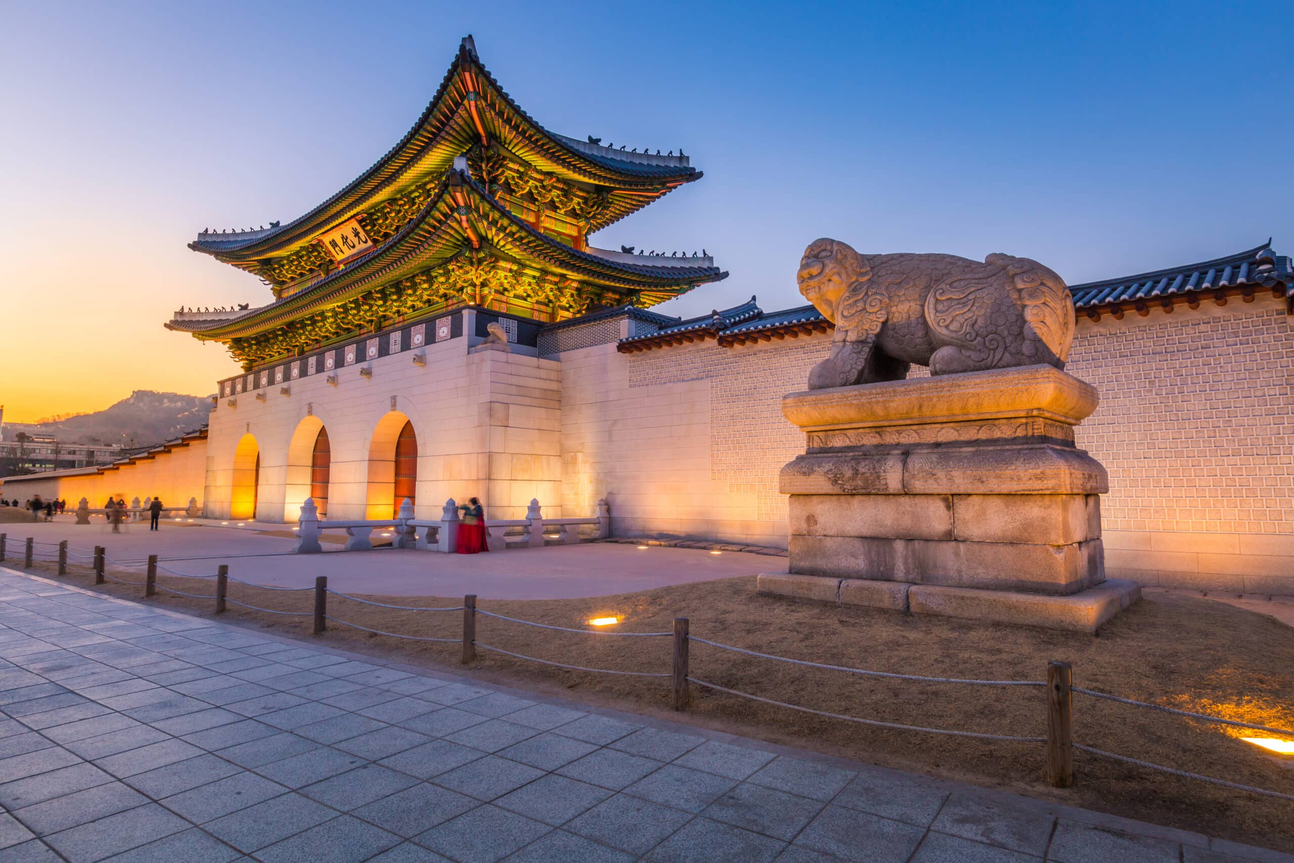 Gyeongbokgung Palace gate in Seoul illuminated in the evening with stone guardian statue