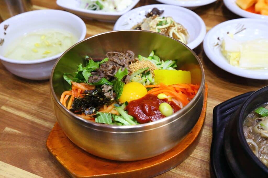 Jeonju bibimbap with vegetables, egg, and chili paste in a metal bowl