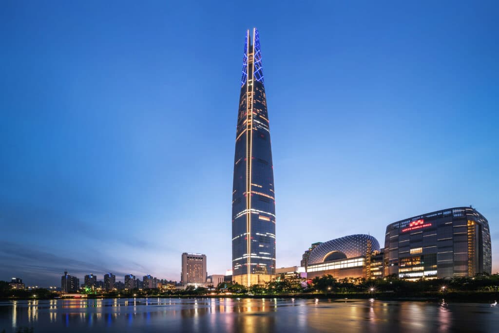Lotte World Tower illuminated at night in Seoul with city skyline reflections