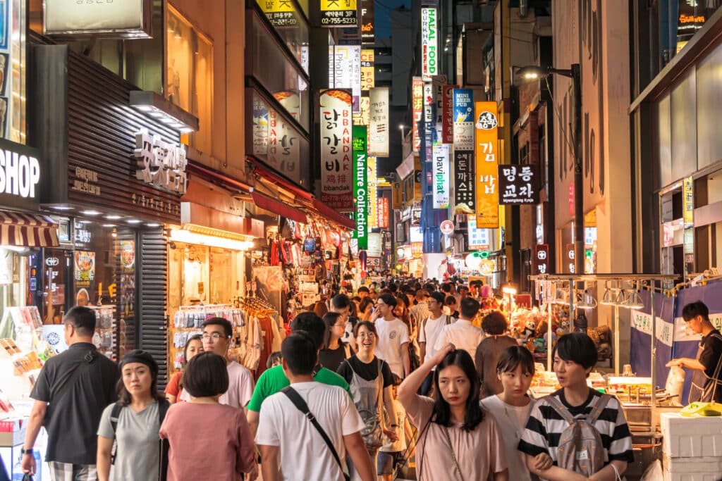 Crowded Myeongdong street at night with food stalls, shops, and neon signs