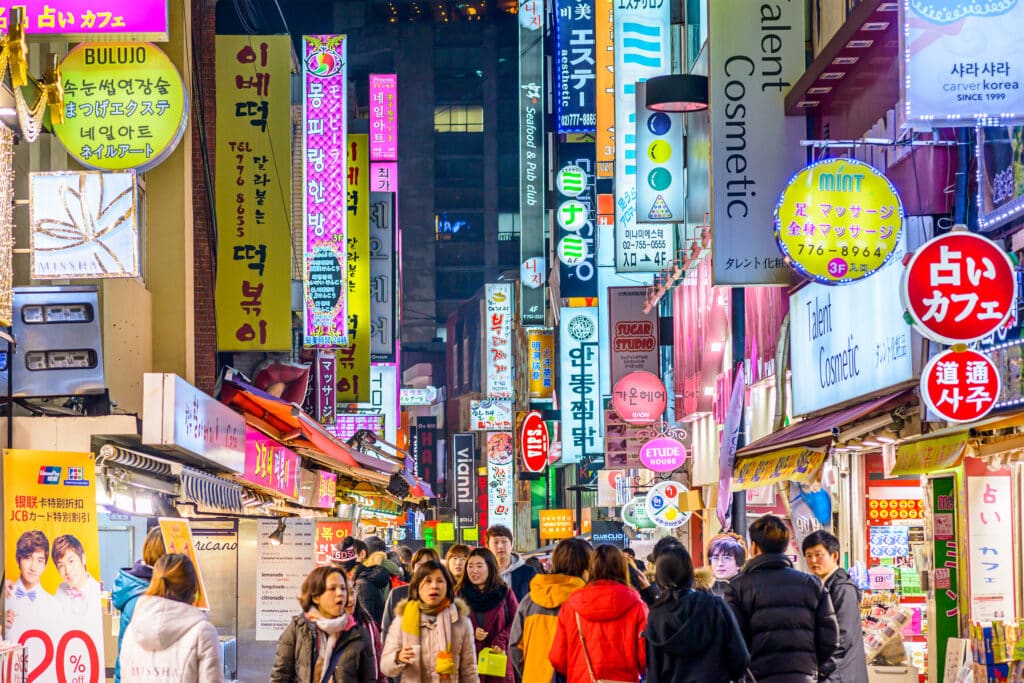 Busy shopping street in Myeongdong, Seoul at night with bright neon signs and crowds