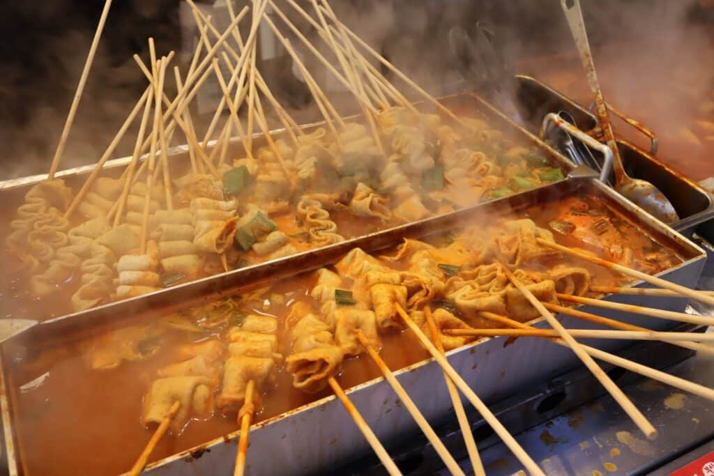 Odeng fish cake skewers cooking in hot broth at a Korean street food stall