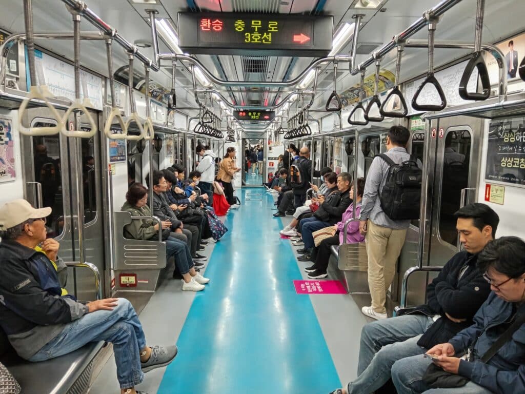 Interior of a Seoul subway train with passengers sitting and standing