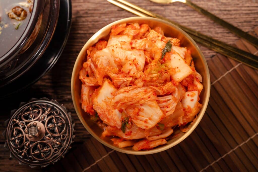 Kimchi Korean pickle and seasoning traditional food, Kimchi salad made with vegetable cabbage and pepper in golden bowl.