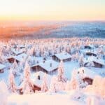 Stunning sunset view over wooden huts and snow covered trees in Finnish Lapland
