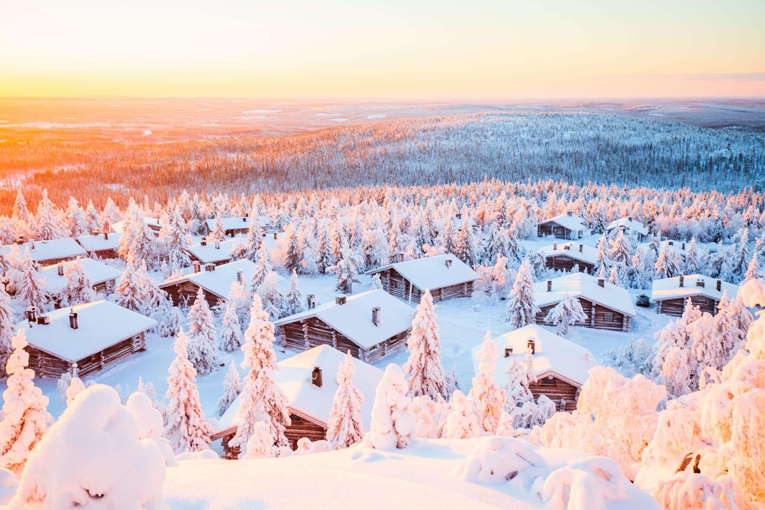 Stunning sunset view over wooden huts and snow covered trees in Finnish Lapland