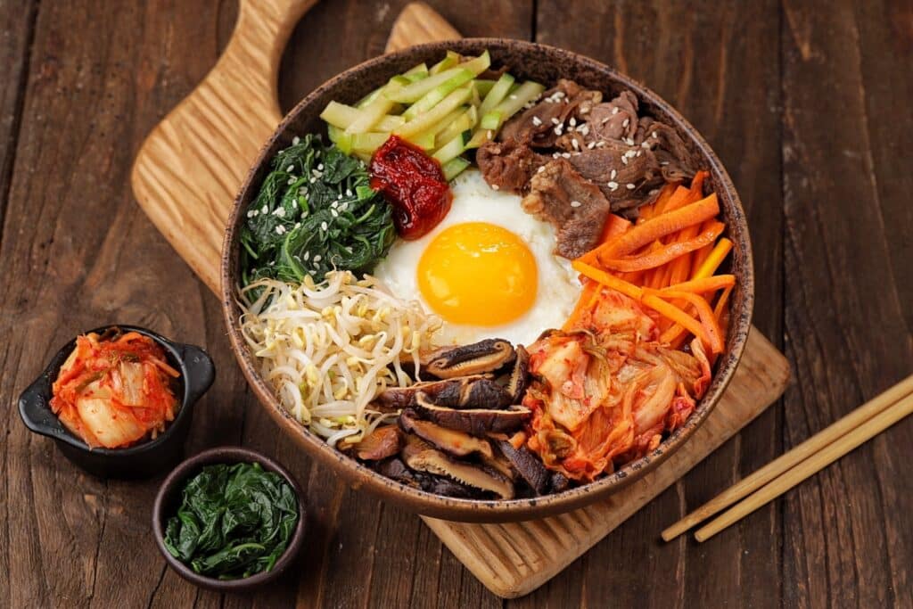 Bibimbap is a Korean dish in the form of a bowl of white rice topped with side dishes of vegetables, beef, eggs and spicy gochujang sauce.