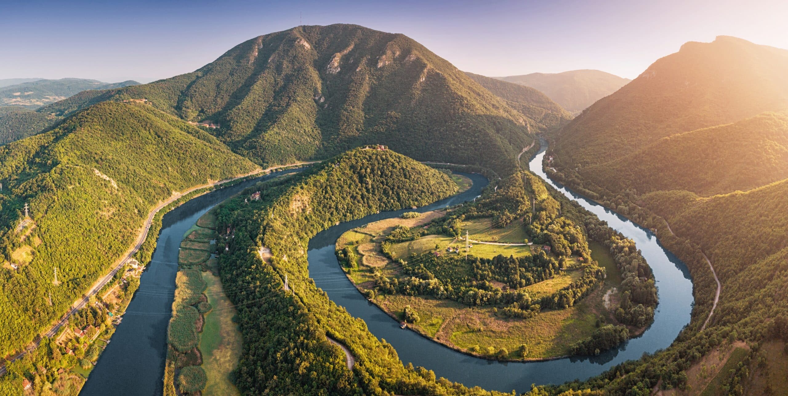 Aerial view of a Western Morava winding river snaking through a picturesque Ovcar Kablar valley, surrounded by lush green mountains in Serbia