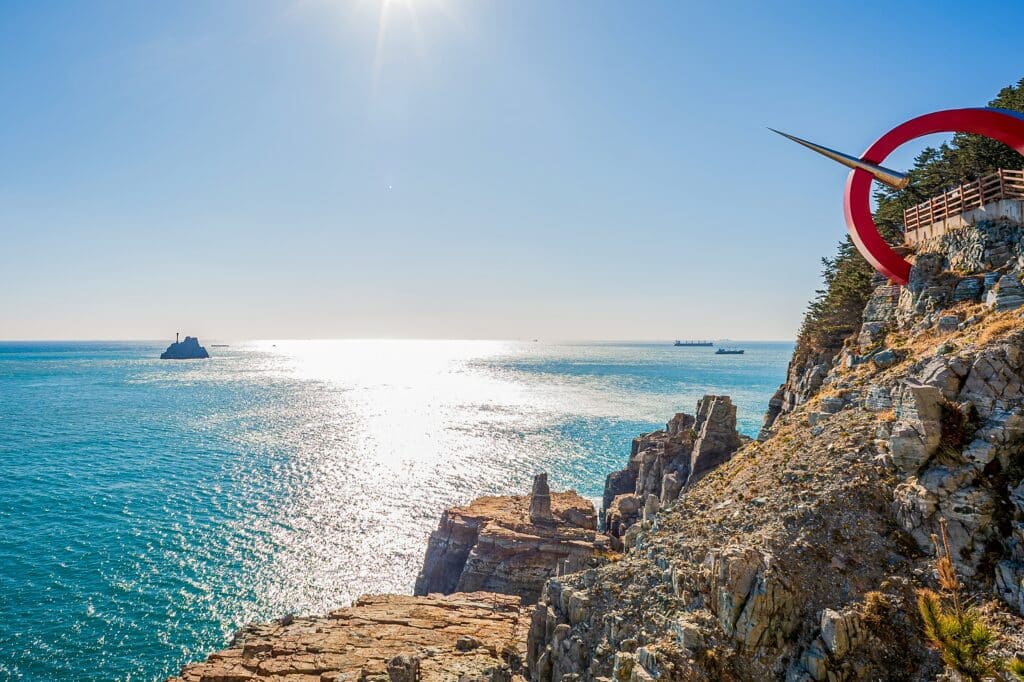 Breathtaking view of the sparkling sea with sun glint and Saengdo Island (Kettle Island) from the rocky cliffs of Taejongdae Resort Park
