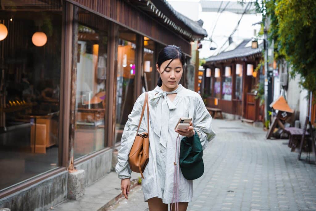 Traveler checking directions on a phone while walking through a traditional-style street in South Korea