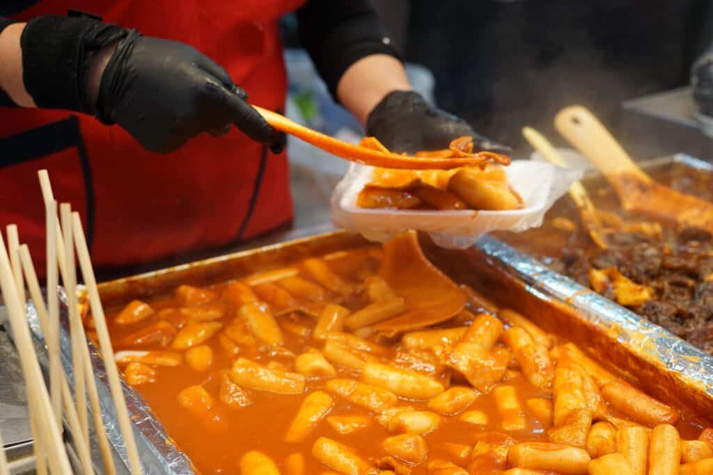 Tteokbokki spicy rice cakes cooking in a red chili sauce at a Korean street food stall