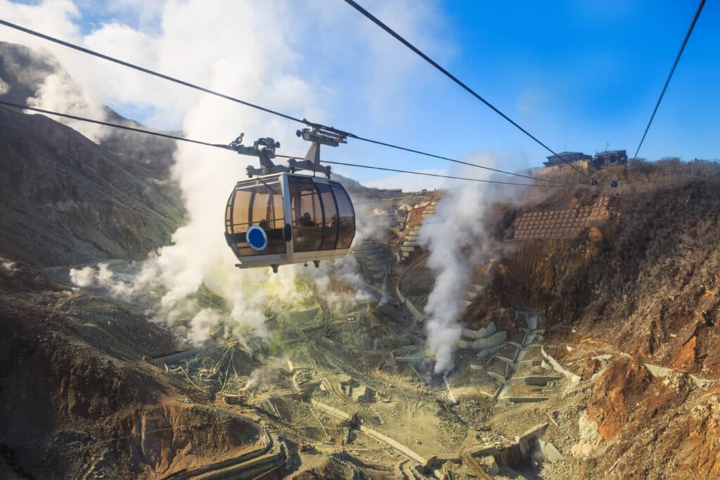 Hakone ropeway gondola passing over Owakudani volcanic valley with steam vents