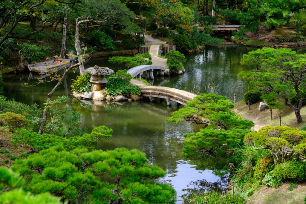 Traditional Japanese garden in Hiroshima with pond and curved stone bridge